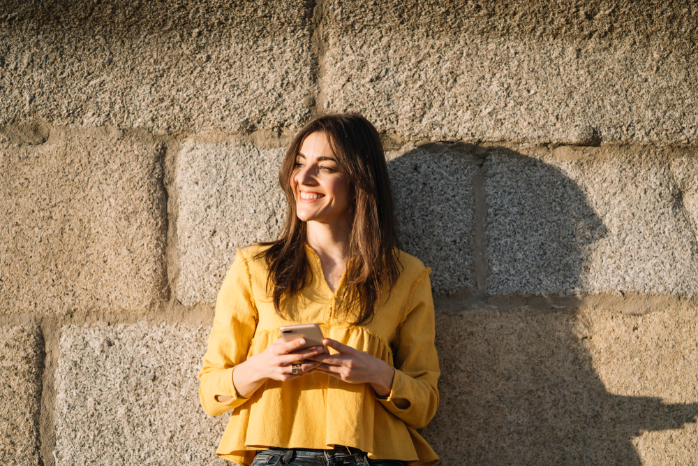 woman in the sun smiling outside of addiction treatment facility